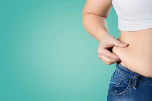Image of woman pinching her love handles to show weight gain Egham